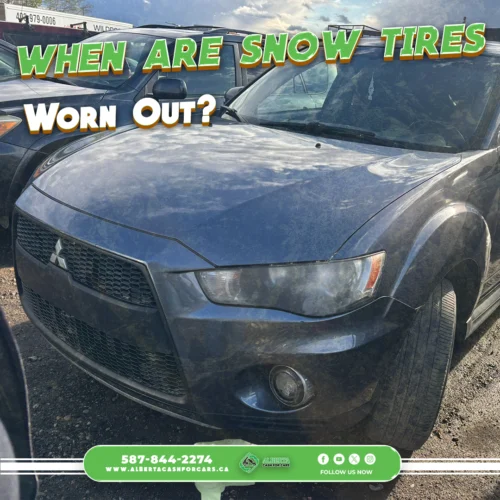 Close-up of a dirty dark gray Mitsubishi SUV front end in a junkyard. Text: When are Snow Tires Worn Out?.