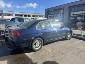 Blue Honda Civic sedan with a "RESERVED PARKING" sign, parked outside a commercial building.